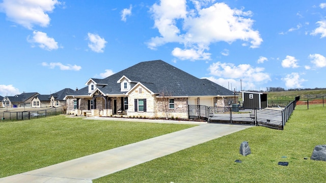 view of front of property featuring brick siding, a shingled roof, fence, a front yard, and an outbuilding