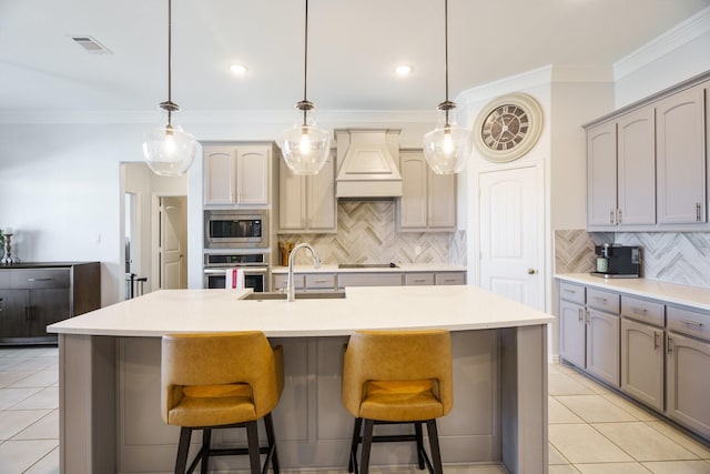 kitchen featuring premium range hood, visible vents, a breakfast bar, stainless steel appliances, and light tile patterned floors