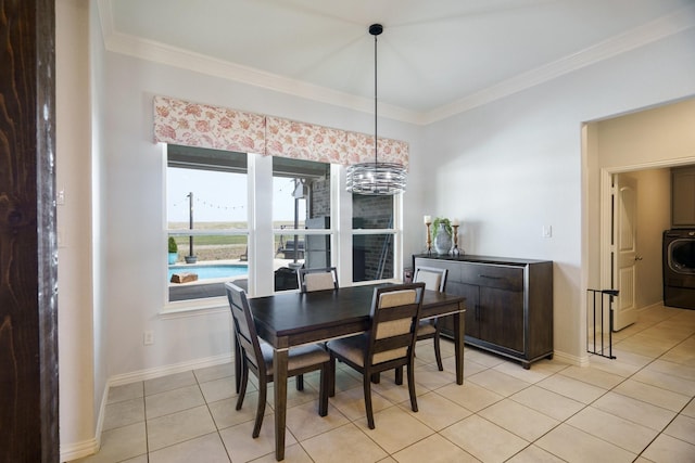 dining space featuring crown molding, light tile patterned floors, baseboards, washer / dryer, and a chandelier