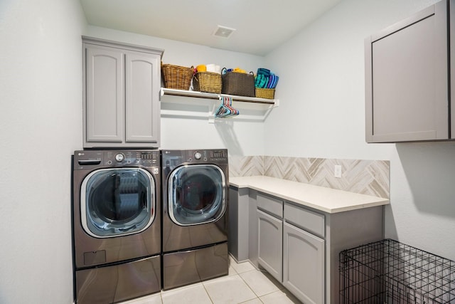 clothes washing area featuring cabinet space, light tile patterned floors, washer and dryer, and visible vents