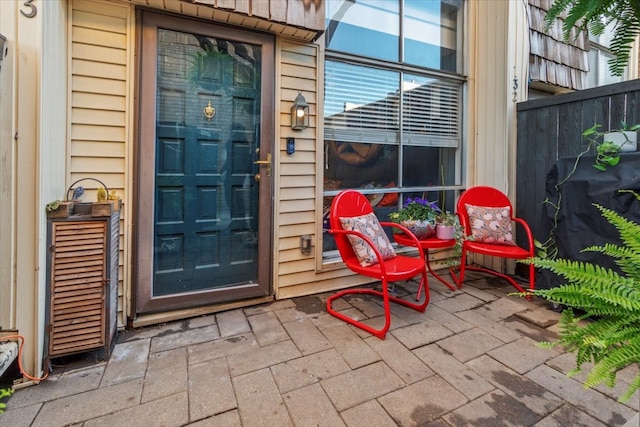 view of exterior entry with a patio area and fence