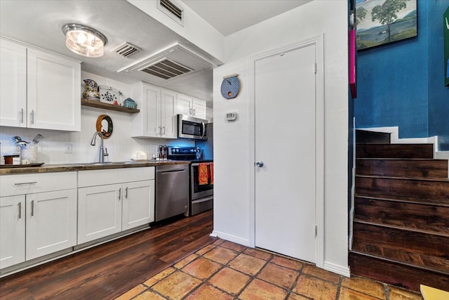 kitchen with visible vents, stainless steel appliances, white cabinetry, open shelves, and a sink