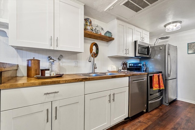 kitchen featuring dark wood finished floors, stainless steel appliances, white cabinetry, open shelves, and a sink