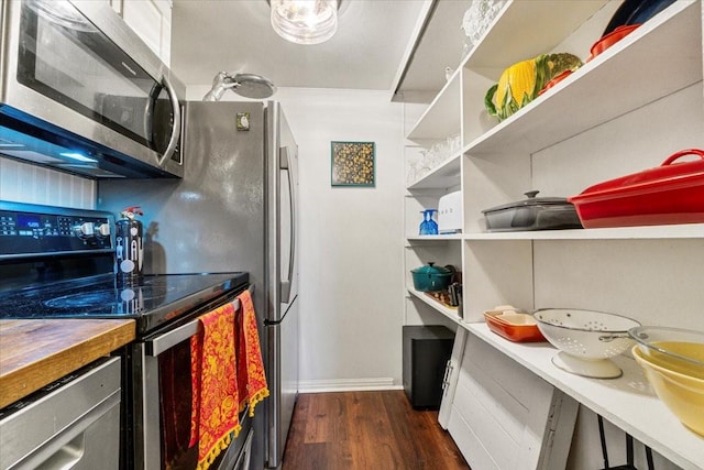 kitchen featuring range with electric cooktop, dark wood finished floors, wood counters, stainless steel microwave, and open shelves