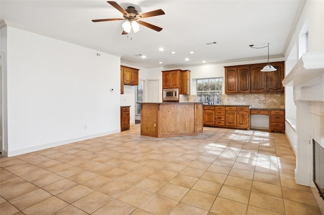 kitchen with visible vents, stainless steel microwave, ornamental molding, a center island, and backsplash