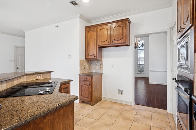 kitchen with appliances with stainless steel finishes, visible vents, ornamental molding, and dark stone countertops