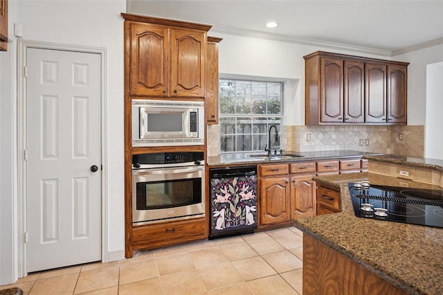 kitchen with crown molding, decorative backsplash, a sink, dark stone countertops, and black appliances