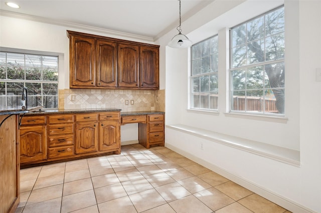 kitchen with light tile patterned flooring, a sink, hanging light fixtures, ornamental molding, and decorative backsplash