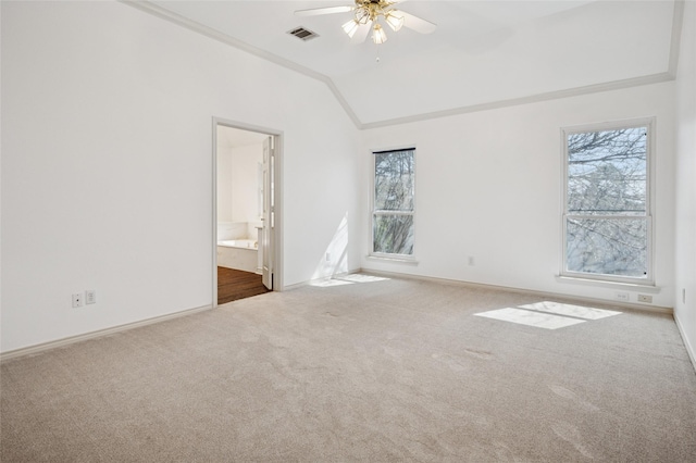 carpeted spare room with lofted ceiling, ceiling fan, visible vents, and baseboards