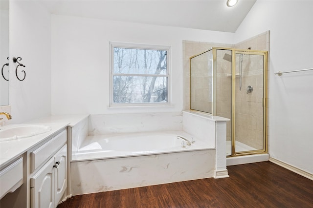 bathroom with lofted ceiling, a garden tub, wood finished floors, vanity, and a stall shower