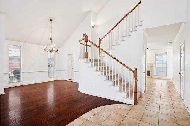 foyer entrance with high vaulted ceiling, wood finished floors, a healthy amount of sunlight, and stairs