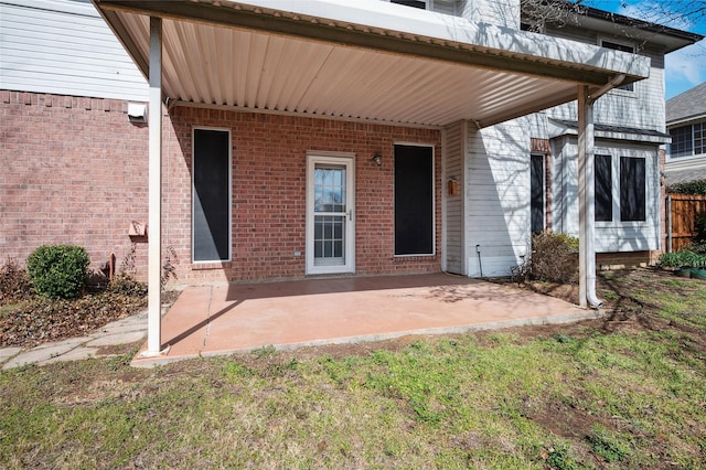 entrance to property featuring brick siding and a patio area