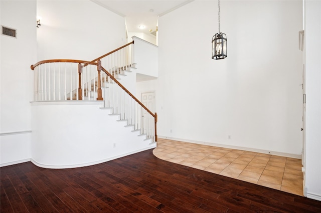 entryway with wood-type flooring, visible vents, a towering ceiling, baseboards, and stairs