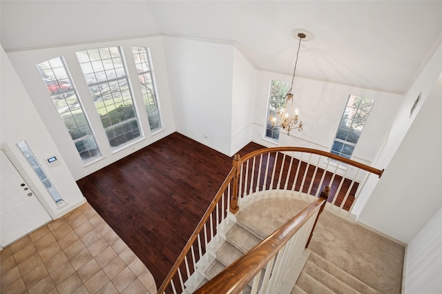 stairway featuring lofted ceiling, baseboards, tile patterned flooring, and an inviting chandelier