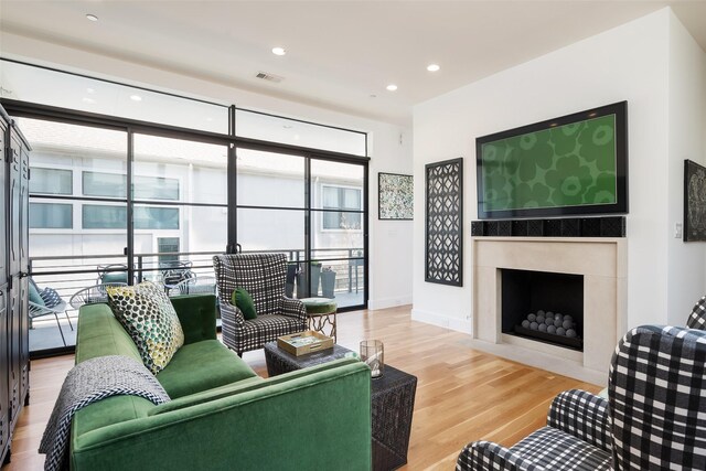 living room featuring visible vents, baseboards, a fireplace with flush hearth, recessed lighting, and wood finished floors