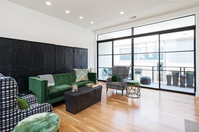 living room featuring recessed lighting, visible vents, a wall of windows, and light wood finished floors