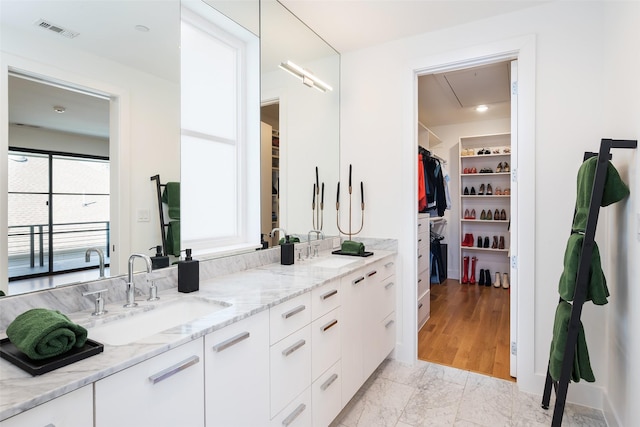 full bath featuring a sink, visible vents, double vanity, and a spacious closet