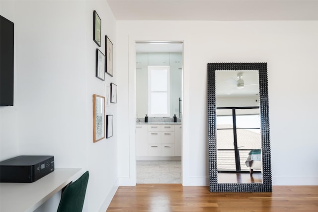 corridor featuring light wood-type flooring and baseboards