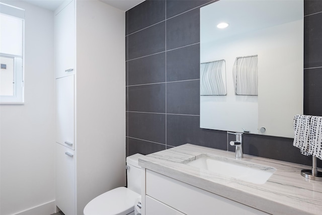 bathroom with recessed lighting, toilet, tile walls, and vanity