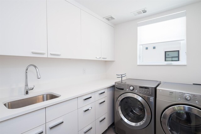 laundry room featuring cabinet space, separate washer and dryer, visible vents, and a sink