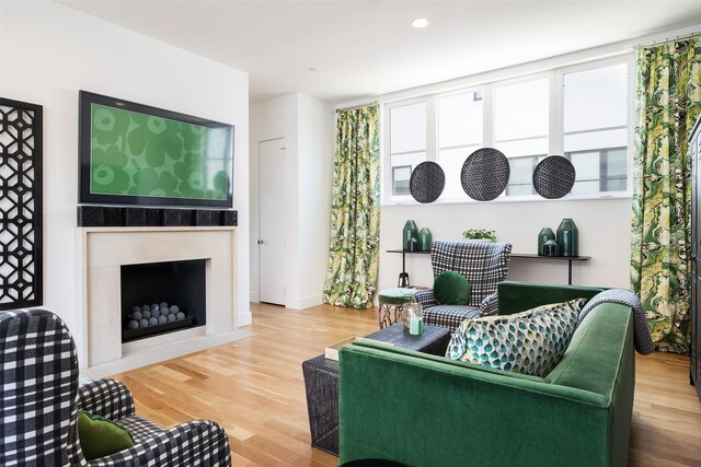 living area featuring a fireplace with flush hearth, recessed lighting, and wood finished floors