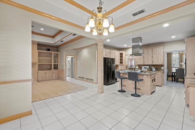 kitchen featuring a breakfast bar, a tray ceiling, island exhaust hood, a kitchen island, and black fridge