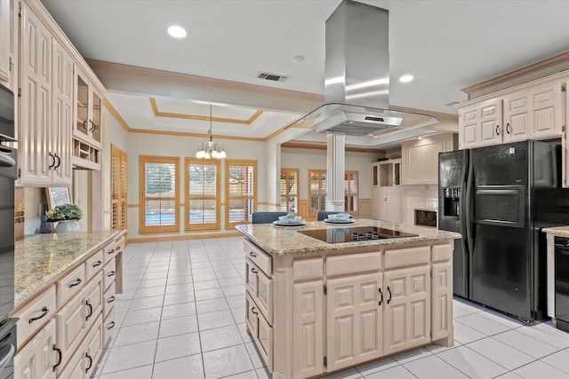 kitchen with visible vents, a kitchen island, island exhaust hood, a tray ceiling, and black appliances