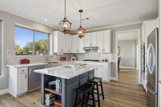 kitchen featuring white cabinets, under cabinet range hood, stainless steel appliances, and a sink