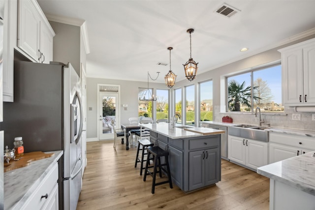 kitchen with visible vents, appliances with stainless steel finishes, ornamental molding, white cabinetry, and a sink