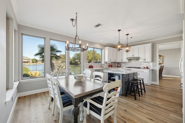 dining room with crown molding, light wood-style flooring, visible vents, and a healthy amount of sunlight