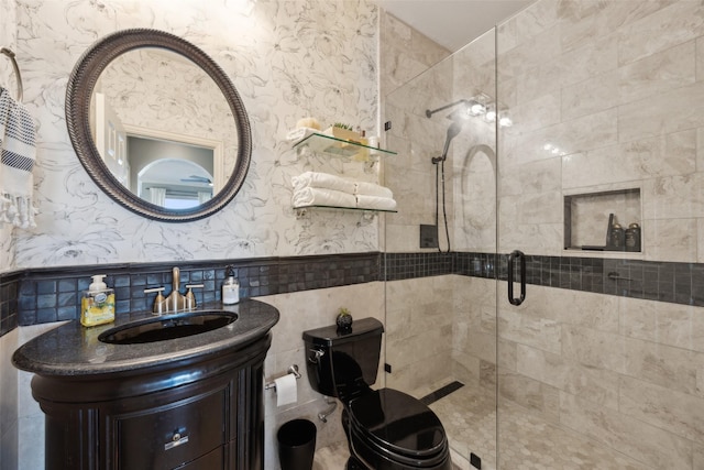 full bathroom featuring a wainscoted wall, tile walls, a shower stall, vanity, and wallpapered walls