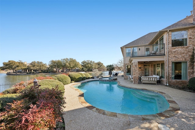 view of pool with a pool with connected hot tub, a water view, a patio, and ceiling fan