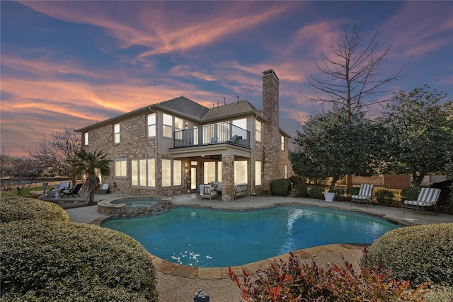 pool at dusk with a pool with connected hot tub, a patio area, and fence