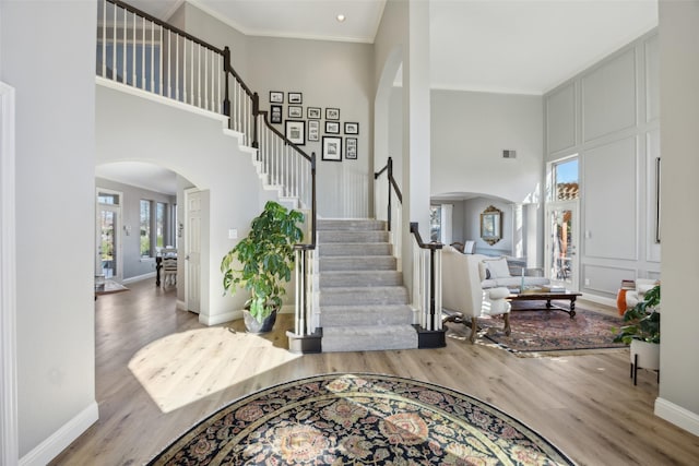 entryway featuring arched walkways, a high ceiling, wood finished floors, and stairs