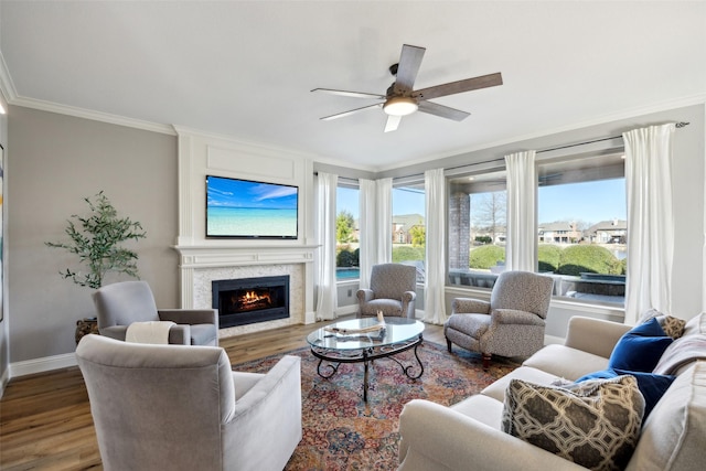 living room featuring baseboards, a lit fireplace, wood finished floors, and crown molding