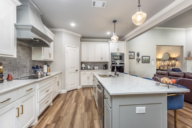 kitchen featuring visible vents, open floor plan, stainless steel appliances, premium range hood, and a sink