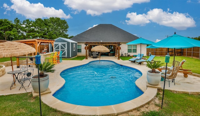 view of swimming pool with a fenced backyard, an outdoor structure, outdoor dry bar, a shed, and a patio area