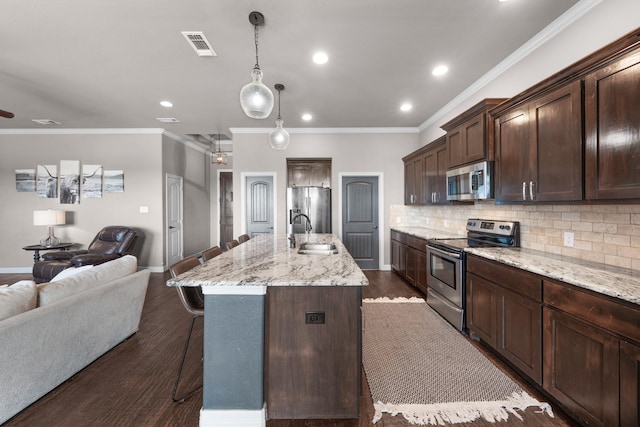 kitchen featuring decorative backsplash, a breakfast bar, open floor plan, stainless steel appliances, and a sink