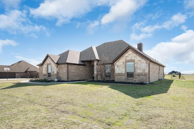 french provincial home featuring brick siding, fence, a chimney, and a front lawn