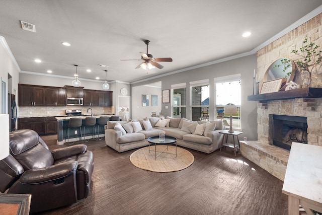 living area with a fireplace, recessed lighting, visible vents, ornamental molding, and ceiling fan