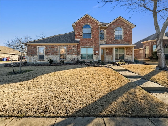 traditional-style home featuring stone siding, roof with shingles, and brick siding