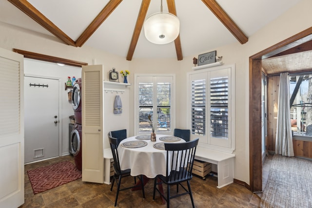 dining area with vaulted ceiling with beams, stacked washer and dryer, baseboards, and stone finish floor