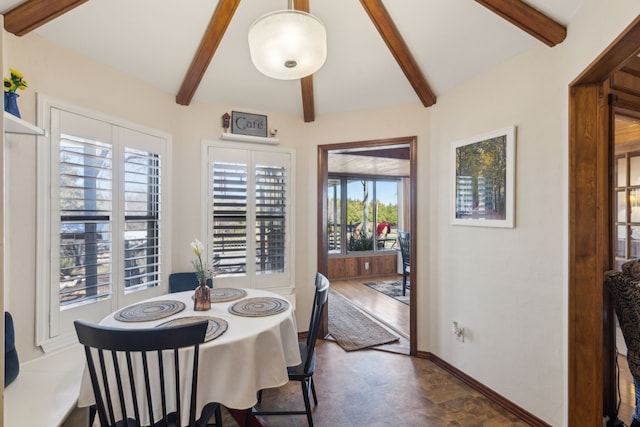 dining room featuring lofted ceiling with beams and baseboards