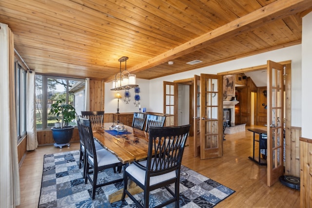 dining area with wooden ceiling, a fireplace, visible vents, light wood-style floors, and wainscoting