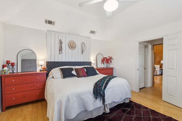 bedroom with a ceiling fan, visible vents, vaulted ceiling, and wood finished floors