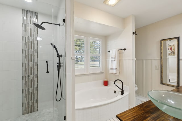 full bath featuring a stall shower, toilet, a wainscoted wall, a garden tub, and a sink