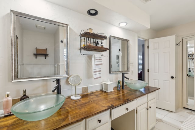 full bathroom with double vanity, a sink, and tile patterned floors