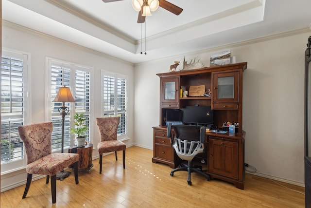 office area with light wood finished floors, a tray ceiling, a ceiling fan, and crown molding