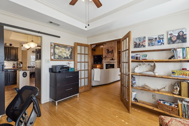 office space featuring french doors, crown molding, a raised ceiling, visible vents, and light wood-style floors