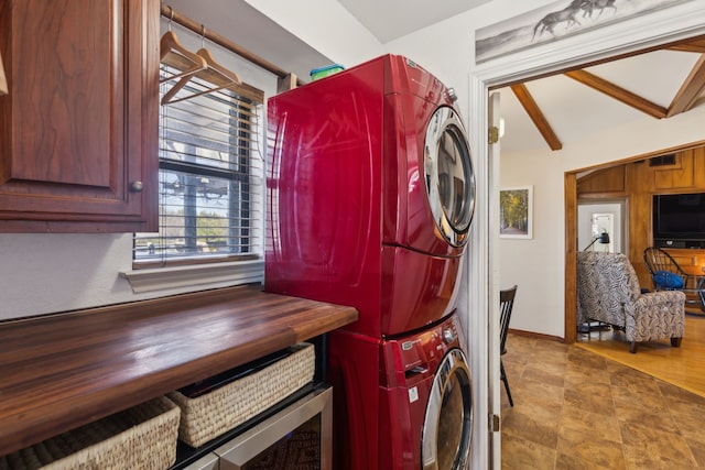 washroom with stone finish floor, visible vents, baseboards, and stacked washer and clothes dryer